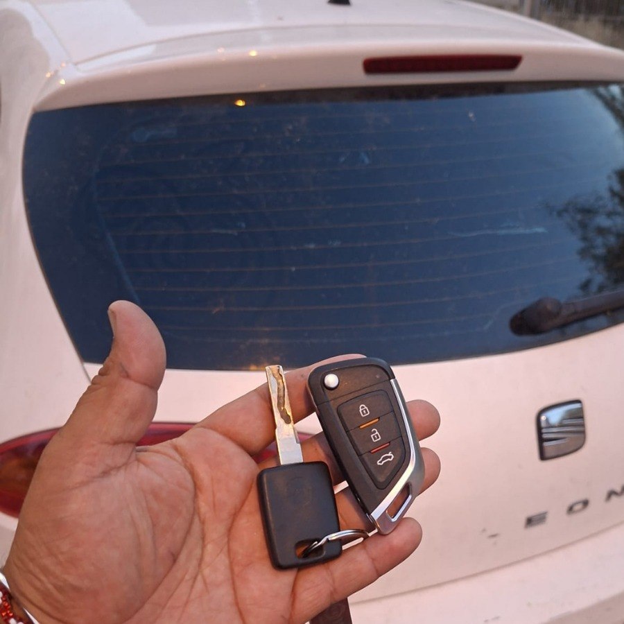 Llave y mando duplicado para vehículo delante de un coche